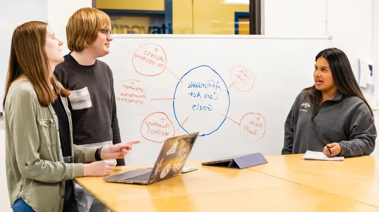 Three students discussing health law in the Makerspace